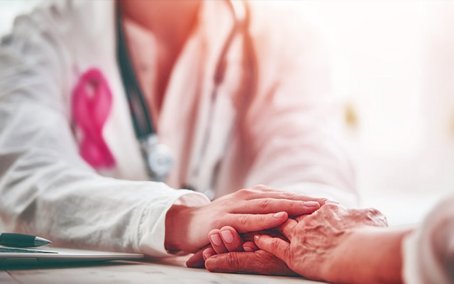 Oncologist holding elderly patient hand during cancer consultation showing compassionate care and personalised treatment support in Kolkata